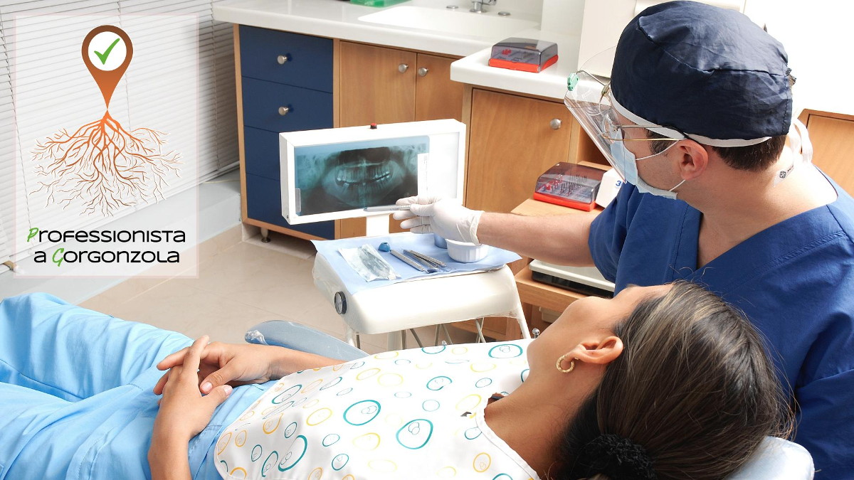 Dentista a Gorgonzola. Se cerchi un dentista a Gorgonzola lo trovi nel portale Studio dentistico: a fianco di una paziente distesa sulla poltrona, il dentista esamina la radiografia